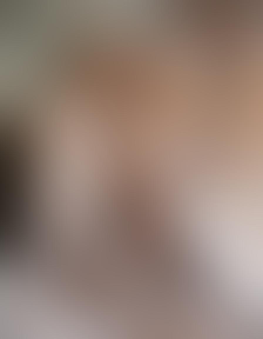 A serene and artistic nude photography scene featuring gorgeous blonde models posed gracefully among soft draped fabrics and delicate flower arrangements. The lighting should be warm and inviting, evoking a sense of intimacy and aesthetic beauty. The background can showcase subtle pastel colors to enhance the ethereal mood. super-realistic. warm tones. soft focus.